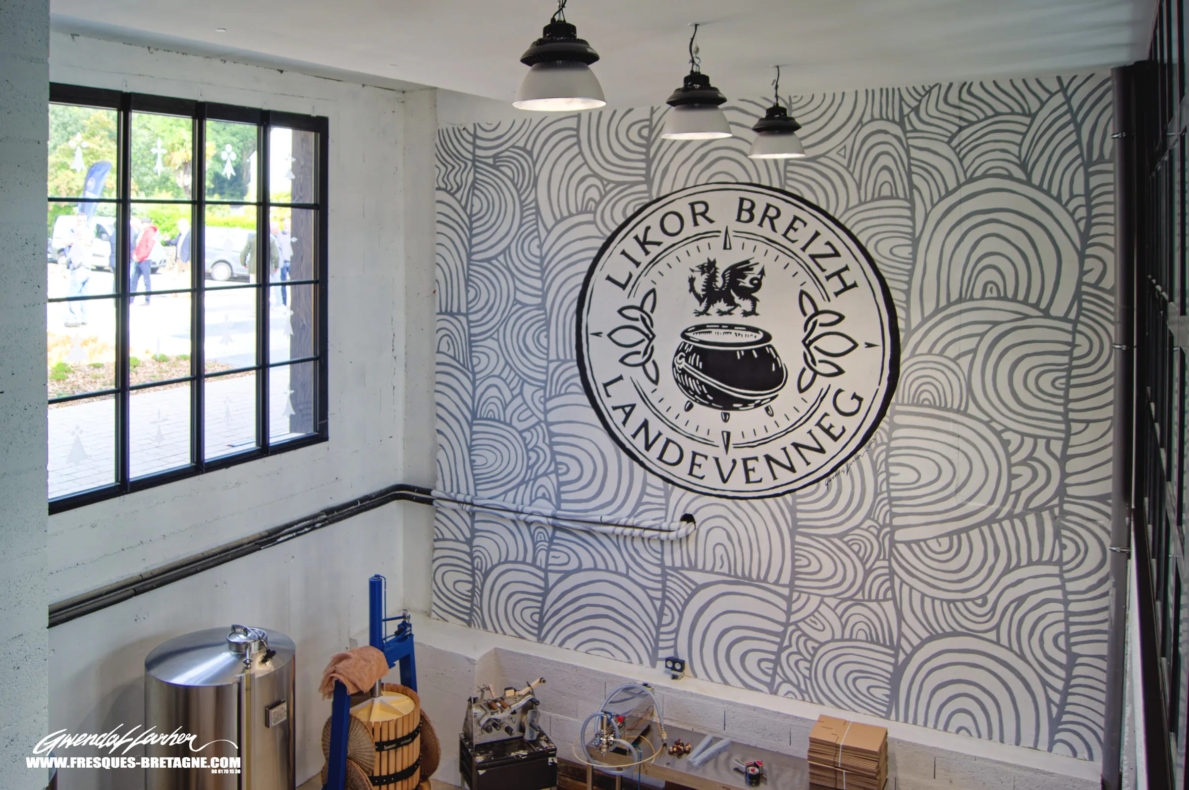 Mur de show-room peint d'arcs et de lignes ondulantes noirs sur fond blanc autour d'un médaillon de distillerie, décor mural contemporain à Landévennec